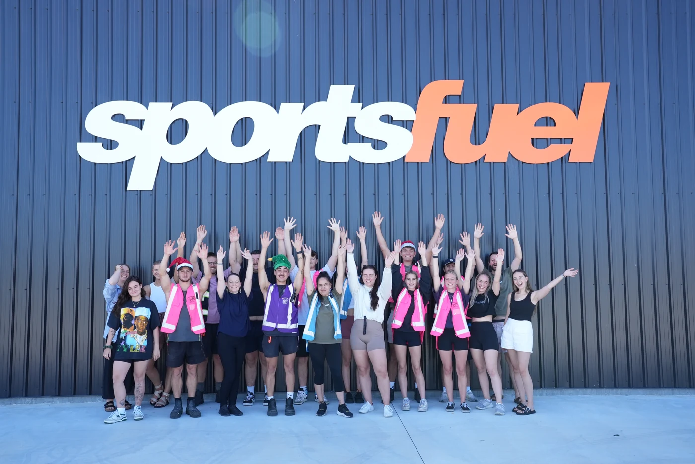 The Sportsfuel team smiling and raising their hands beneath the Sportsfuel sign